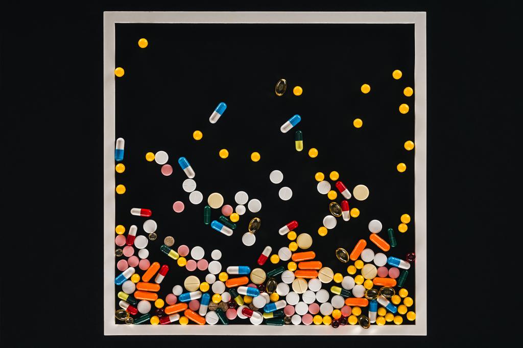 vista dall'alto della cornice con mucchio colorato varie pillole isolate sul nero
  - Foto, immagini