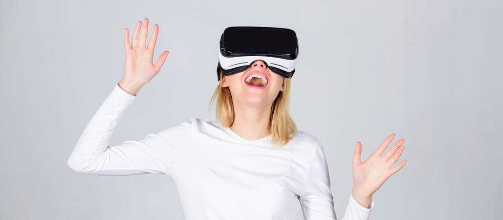 Retrato de una chica sorprendida usando un casco de realidad virtual aislado sobre fondo gris. Mujer feliz explorando mundo aumentado, interactuando con la interfaz digital. Auriculares de realidad virtual
 - Foto, Imagen