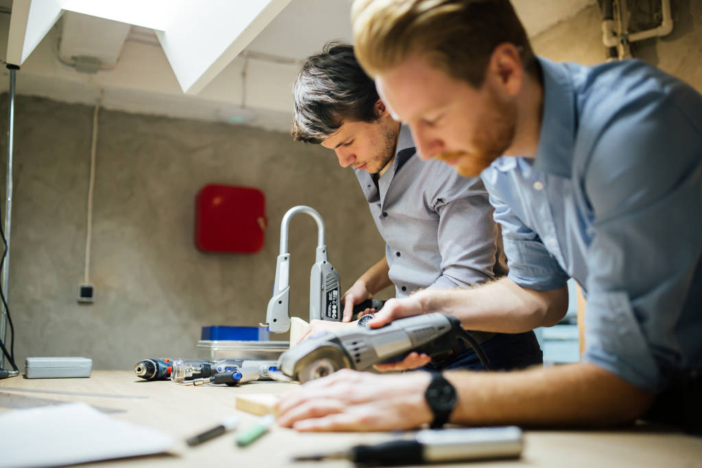 Δύο δημιουργικές σχεδιαστών που εργάζονται σε εργαστήριο με εργαλεία ακριβείας κατασκευή ενός νέου προϊόντος - Φωτογραφία, εικόνα