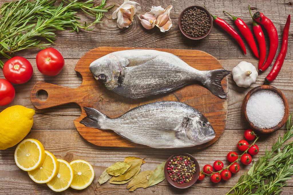 složení potravin syrových ryb na dřevěné desce, obklopen ingredience na stole - Fotografie, Obrázek