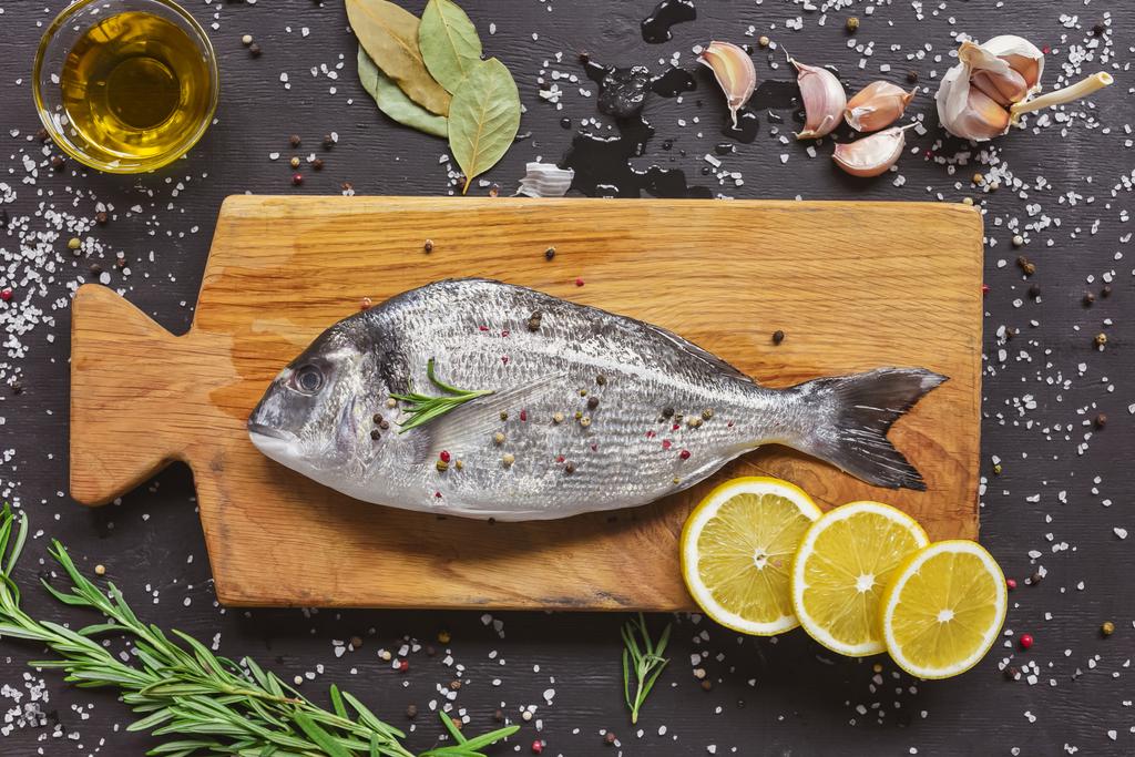 Ansicht der Nahrungsmittelzusammensetzung mit rohem Fisch und Zutaten auf Holzbrett - Foto, Bild