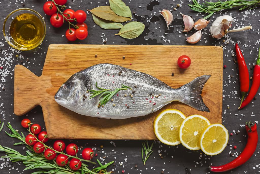 θέα από ψηλά της σύνθεσης των τροφίμων με ωμό ψάρι και συστατικά σε ξύλινη σανίδα - Φωτογραφία, εικόνα