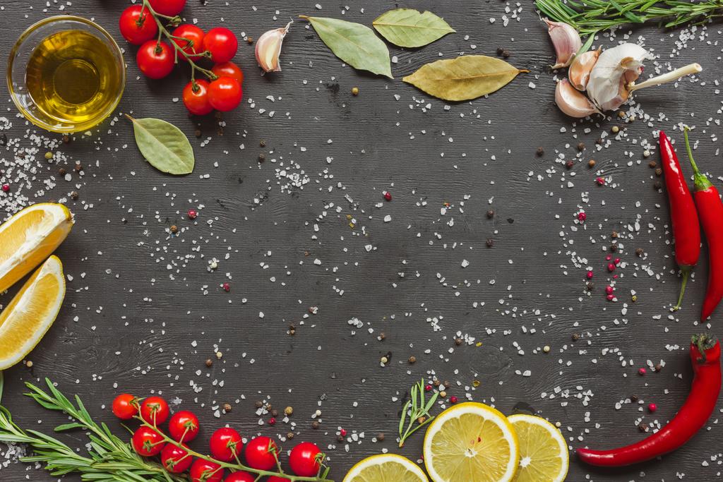 kiraz domates, sarımsak, limon, biberiye, biber ve zeytinyağı cam üst görünümünü siyah masada  - Fotoğraf, Görsel
