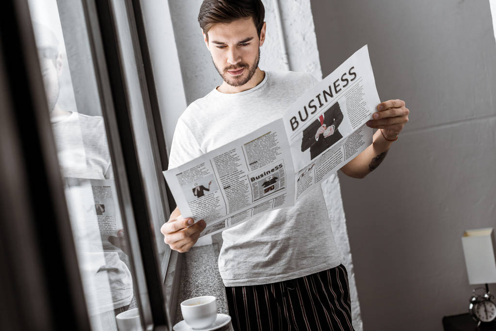 csinos, fiatal férfi olvasó teendő újság otthon   - Fotó, kép