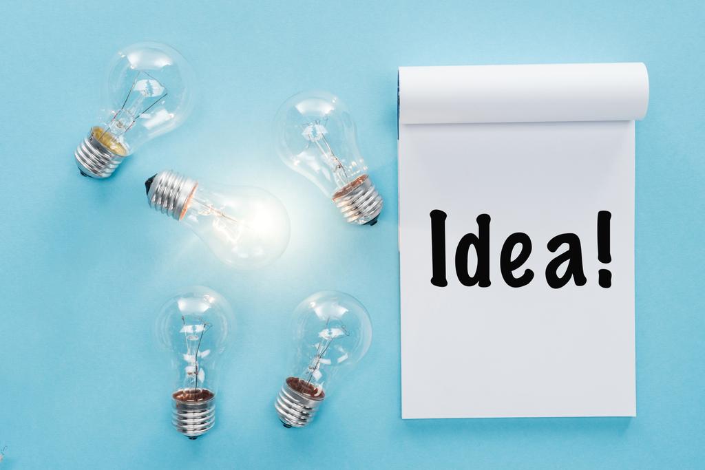 Notizbuch mit 'Idee' Wort in der Nähe von Glühbirnen mit glühenden ein, mit neuen Ideen Konzept - Foto, Bild