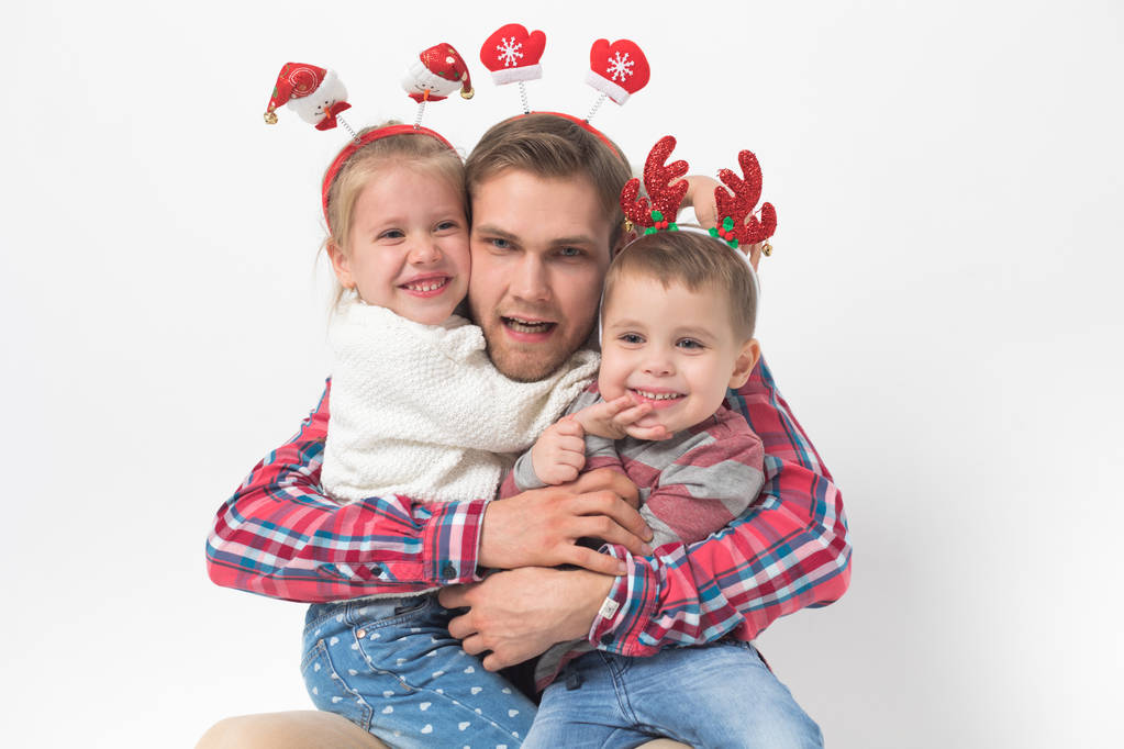 Отец с детьми в смешных рождественских повязках на белом фоне
. - Фото, изображение