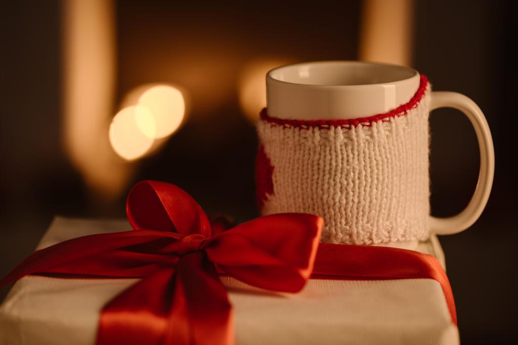 regalo con fiocco e tazza lavorata a maglia su fondo sfocato
 - Foto, immagini
