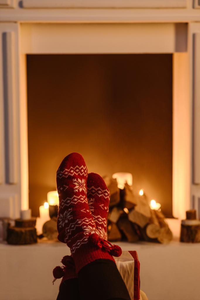 vista recortada de la mujer en calcetines de invierno festivos con chimenea en el fondo
 - Foto, Imagen