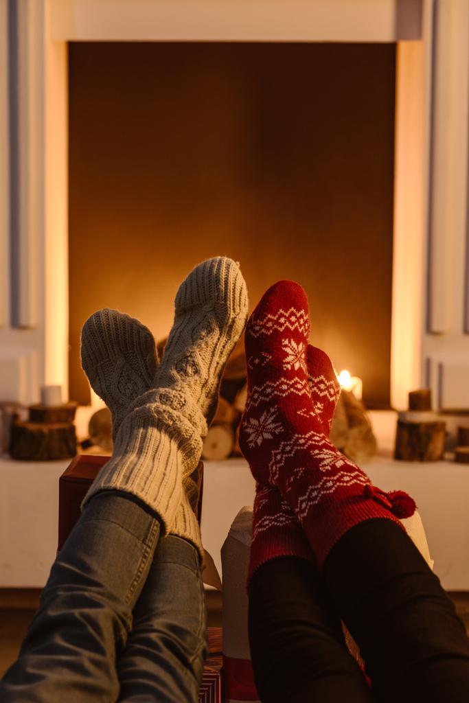 vista cortada de mulheres vestindo meias de inverno com lareira no fundo
 - Foto, Imagem