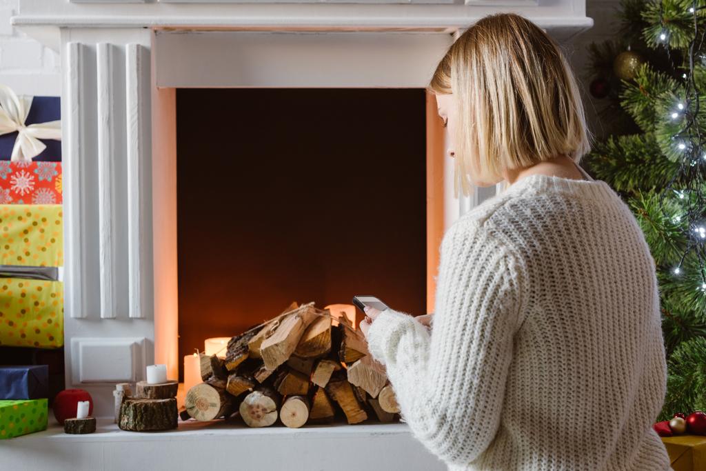 young woman sitting near fireplace with firewood - Photo, Image