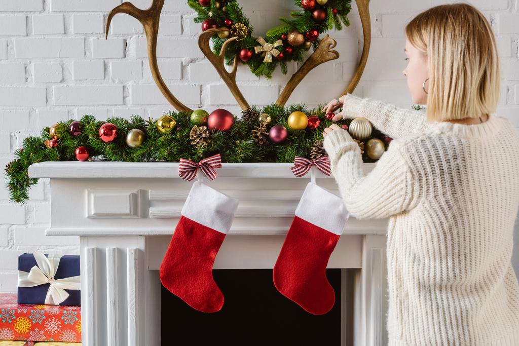 jeune femme ajuster boules de Noël à la cheminée
 - Photo, image