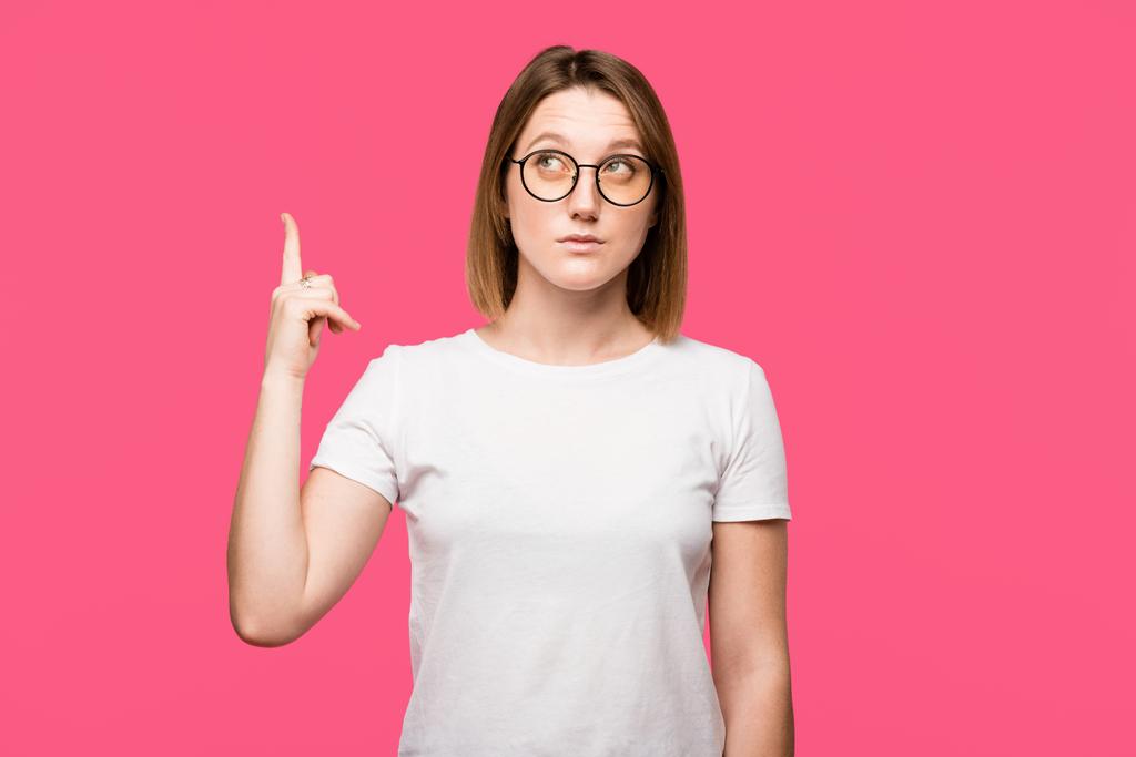 attractive young woman in eyeglasses doing idea gesture isolated on pink - Photo, Image