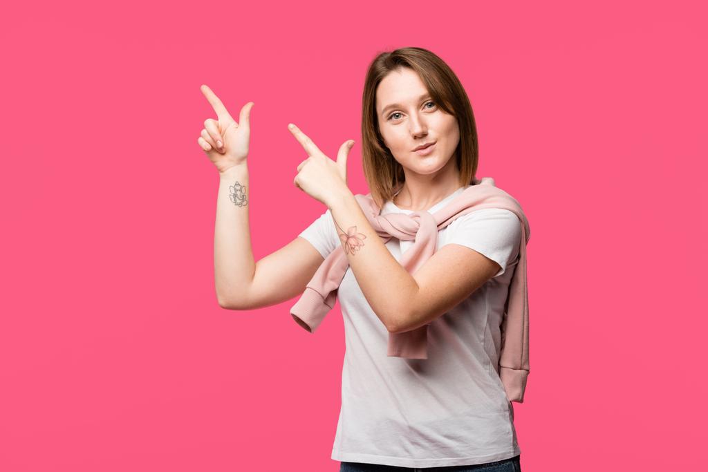 happy tattooed woman pointing by fingers isolated on pink - Photo, Image