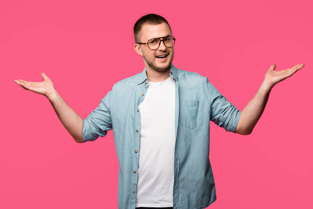 knappe man in brillen permanent met open armen en lachend op camera geïsoleerd op roze - Foto, afbeelding