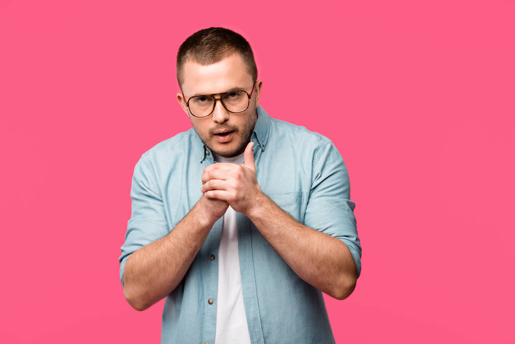 junger Mann mit Brille reibt sich die Hände und blickt isoliert in die Kamera auf rosa - Foto, Bild