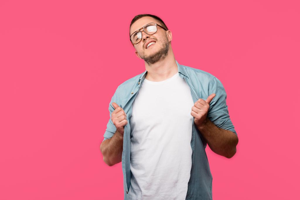 fresco giovane uomo in occhiali tenendo la camicia e mostrando pollici su isolato su rosa
 - Foto, immagini