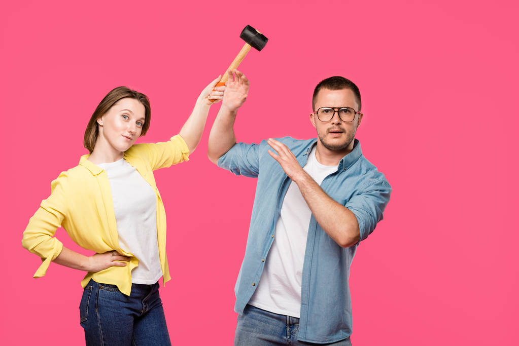 junges Paar mit Hammer blickt isoliert auf rosa Kamera - Foto, Bild