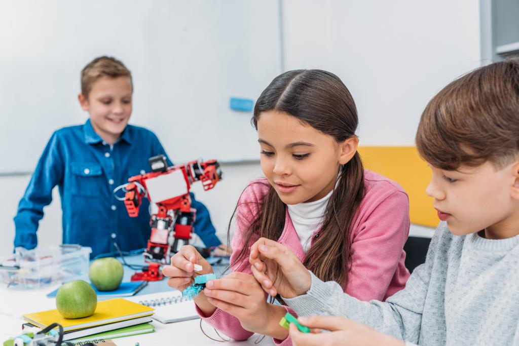 Счастливые одноклассники делают робота во время урока робототехники STEM
  - Фото, изображение