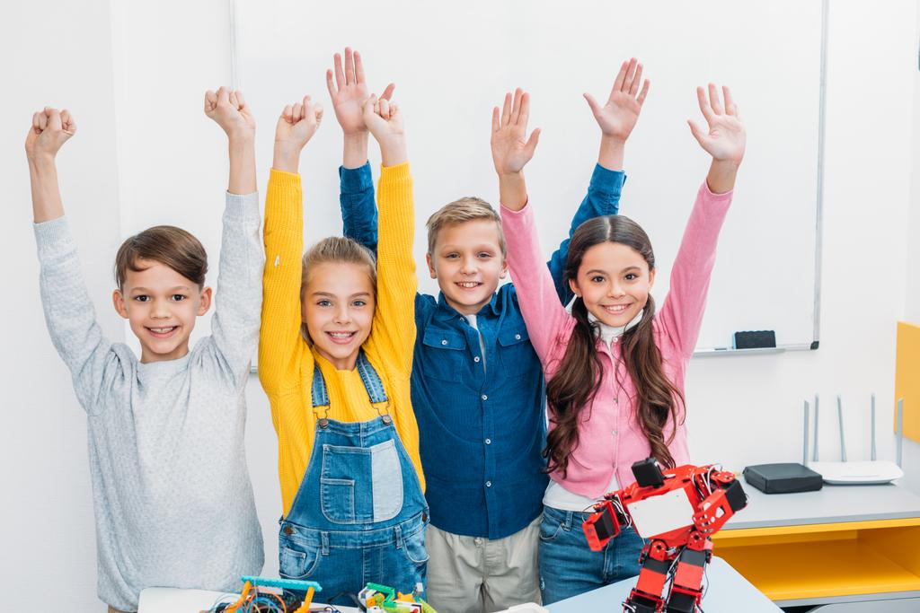 crianças felizes de escola levantando as mãos e olhando para a câmera na aula de tronco
 - Foto, Imagem