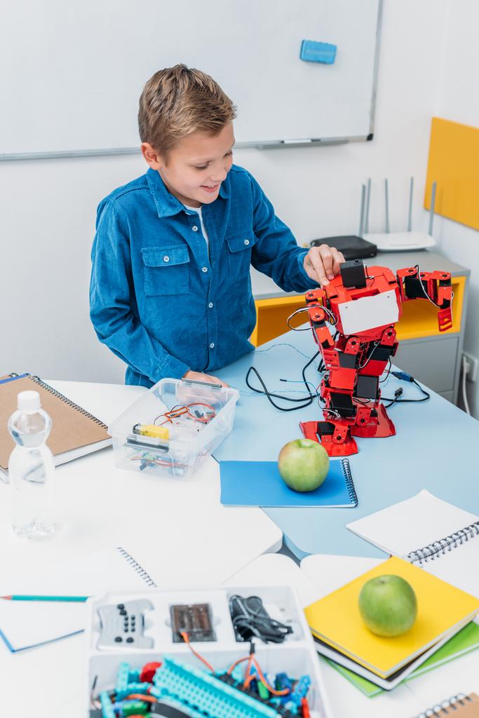 Gelukkig schooljongen werkt aan handgemaakte robot model tijdens stam les   - Foto, afbeelding
