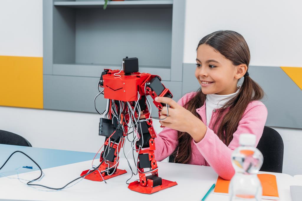 adorabile studentessa seduta a tavola, sorridente e con in mano un modello di robot durante la lezione STEM
   - Foto, immagini