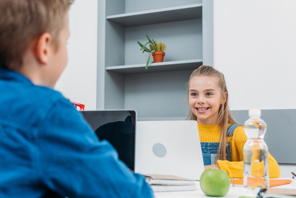 kız öğrenci ve masada oturan, dizüstü bilgisayarlar ve öğrenmeyi sınıf okul çocuğu gülümseyen - Fotoğraf, Görsel