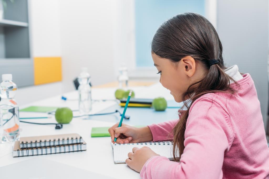 schoolmeisje schrijven in laptop tijdens de les in de klas - Foto, afbeelding