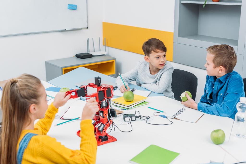 dzieci w wieku szkolnym programowania robota razem i jedzenie jabłek podczas Stem edukacyjnych Klasa - Zdjęcie, obraz