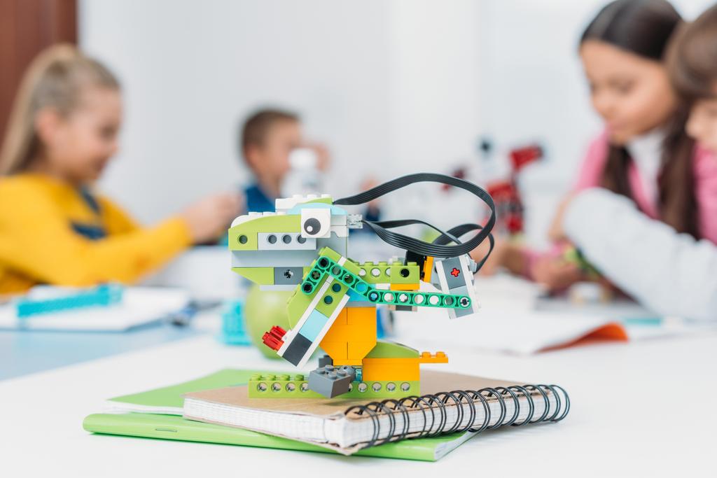 селективный фокус модели робота ручной работы и одноклассников, работающих вместе над проектом во время урока STEM на заднем плане
 - Фото, изображение