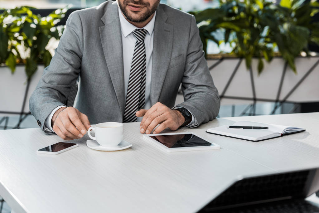 imagen recortada de hombre de negocios tomando una taza de café en la mesa en la oficina
 - Foto, imagen