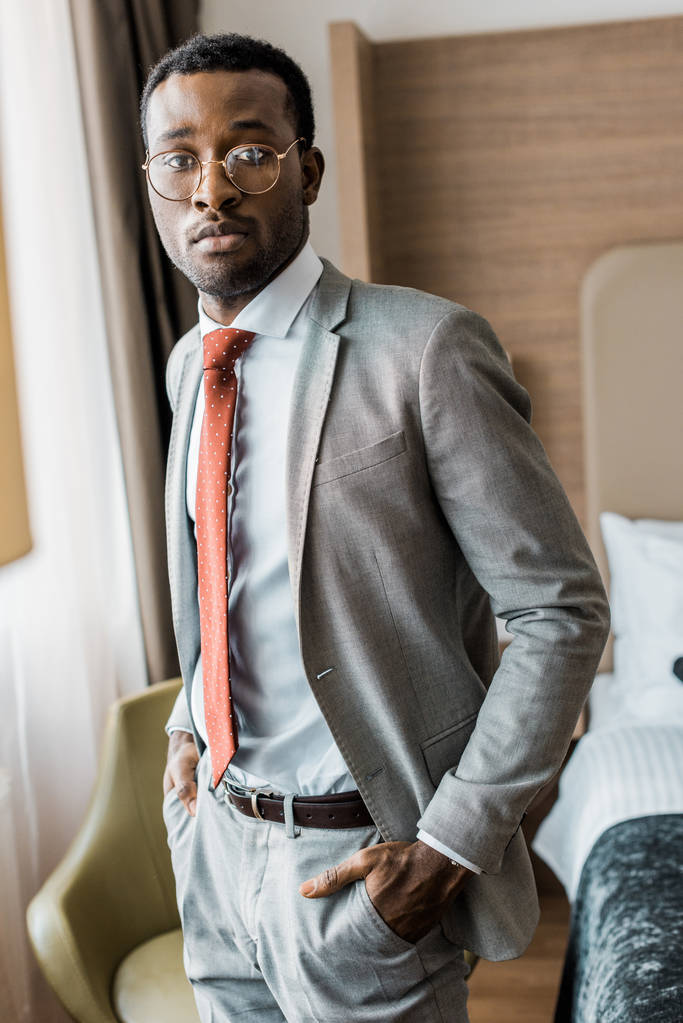 komea liikemies harmaa puku ja punainen solmio poseeraa hotellihuoneessa
 - Valokuva, kuva