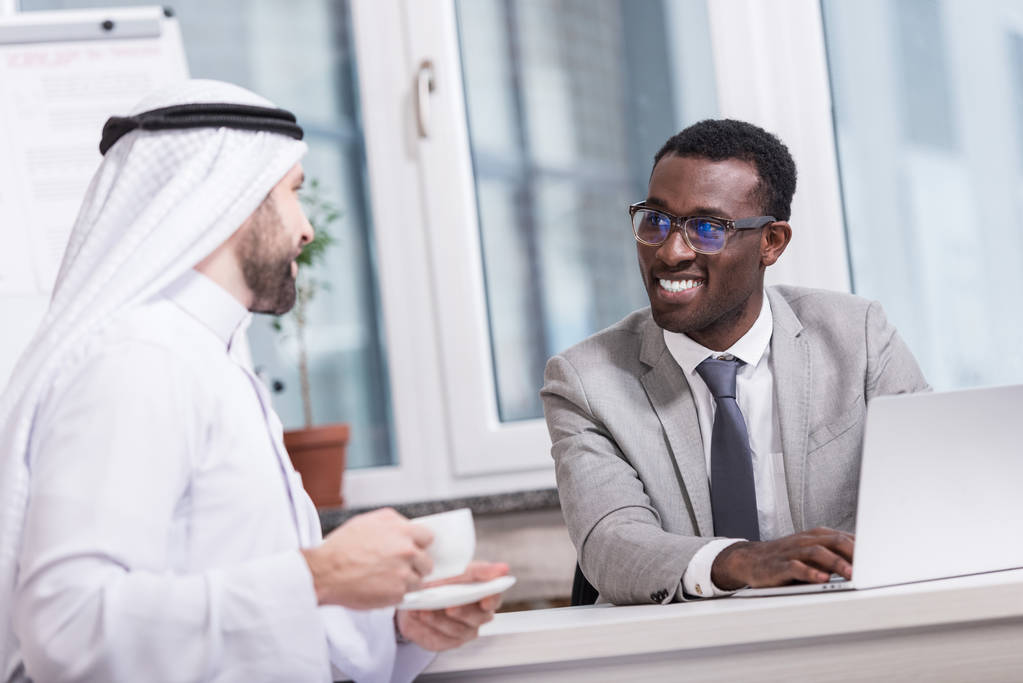 Homme d'affaires afro-américain regardant partenaire arabe avec une tasse de café
 - Photo, image