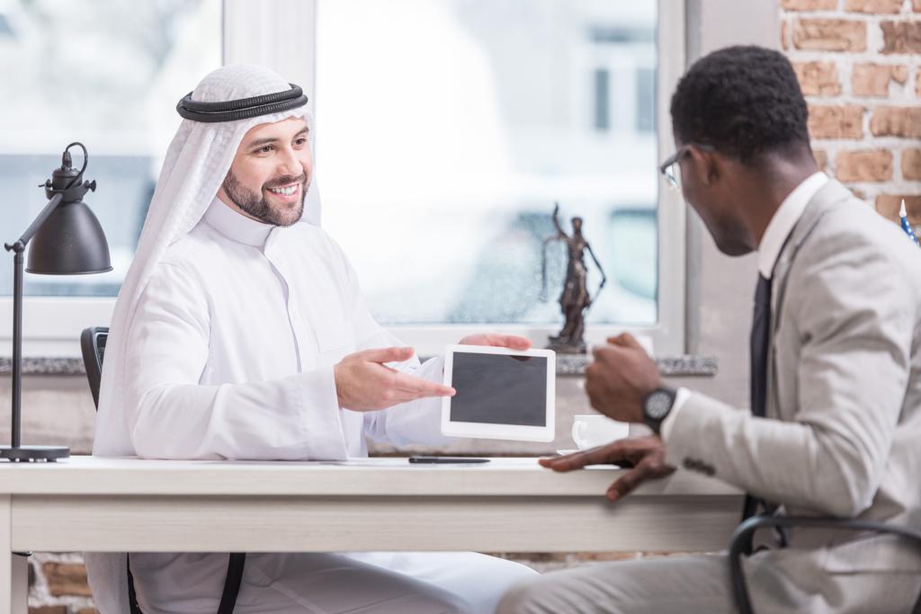 Dijital tablet gösterilen ve ofiste gülümseyen Arap işadamı  - Fotoğraf, Görsel