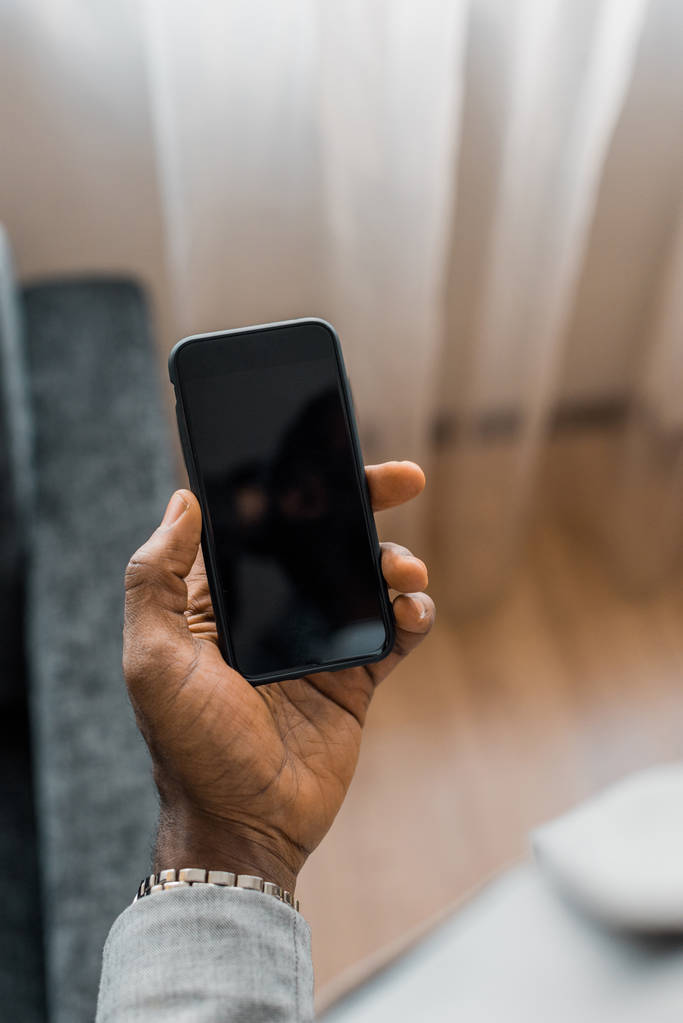 bijgesneden weergave van Afro-Amerikaanse man smartphone met leeg scherm - Foto, afbeelding