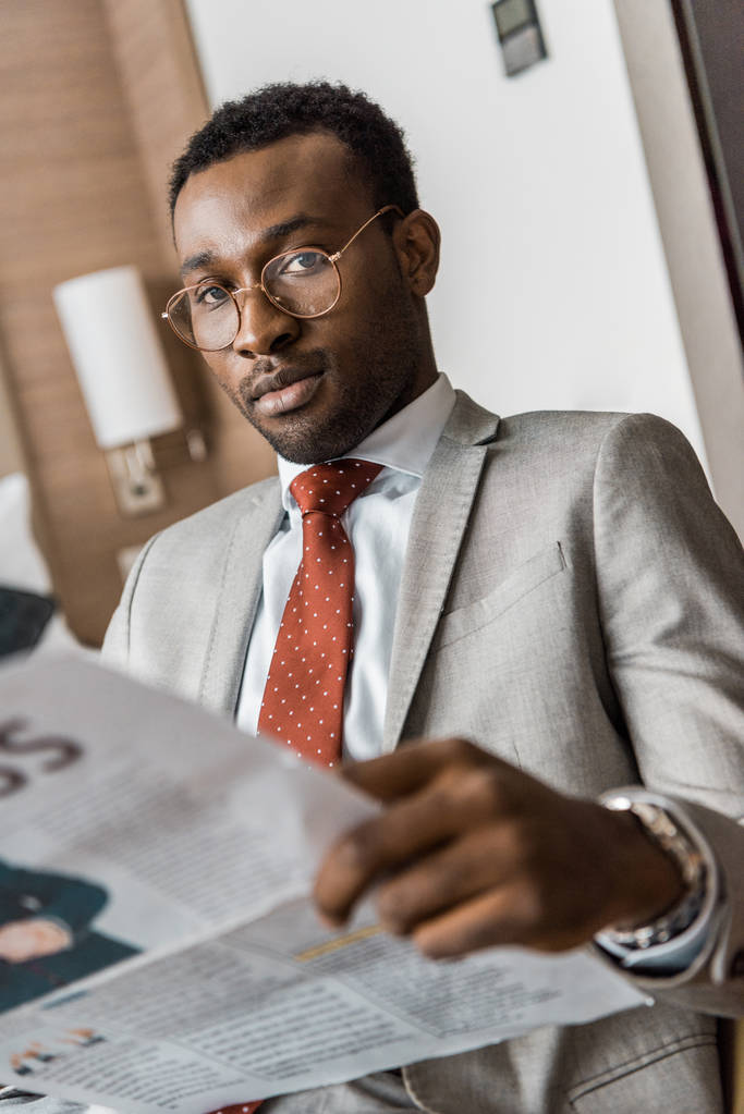 homme d'affaires afro-américain en costume tenant le journal et regardant la caméra
 - Photo, image