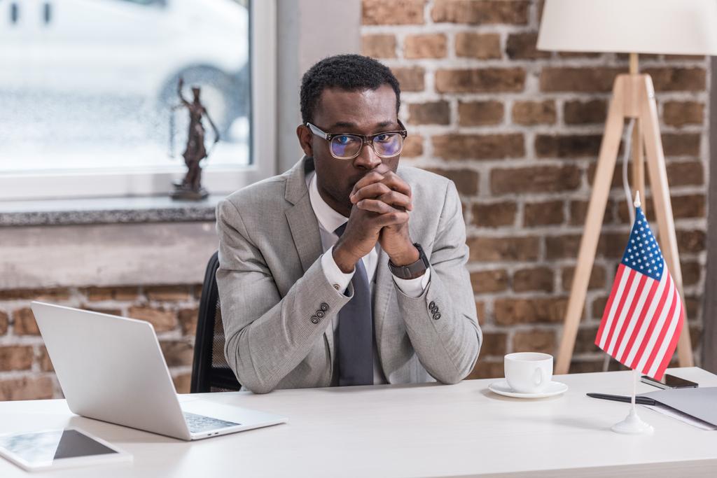 近代的なオフィスのデスクに座っているアフリカ系アメリカ人のビジネスマン  - 写真・画像