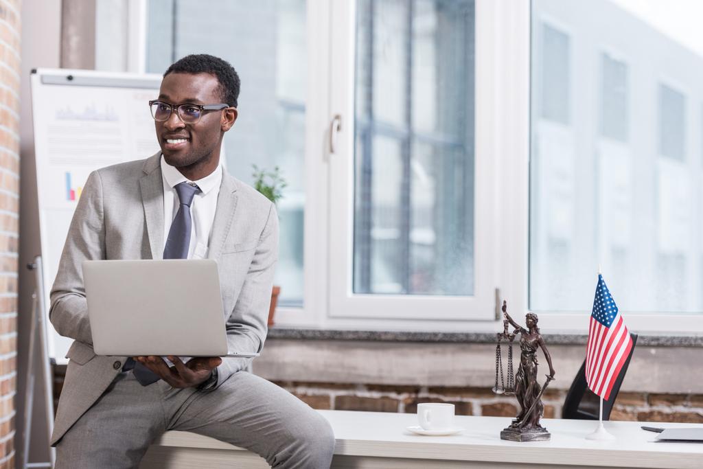 Hombre de negocios afroamericano sosteniendo portátil en oficina moderna
  - Foto, imagen