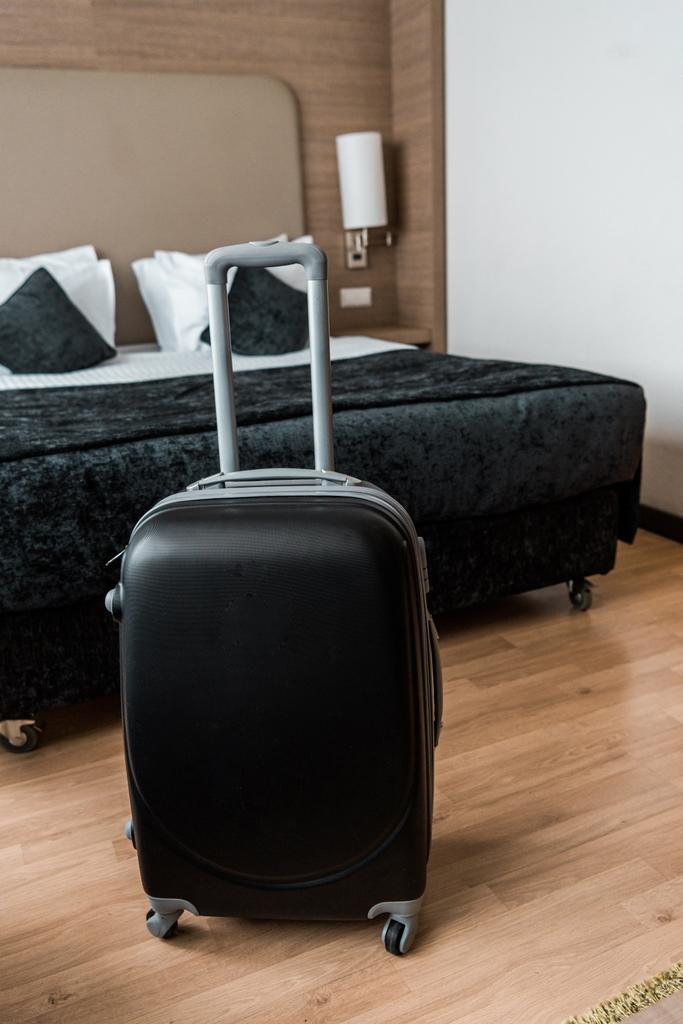 Yataklı otel odasında siyah seyahat çantası - Fotoğraf, Görsel