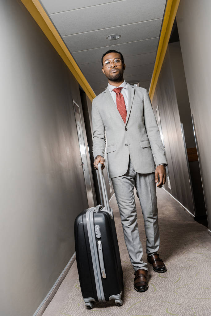 Afro-Amerikaanse zakenman met bagage lopen in hotel gang - Foto, afbeelding