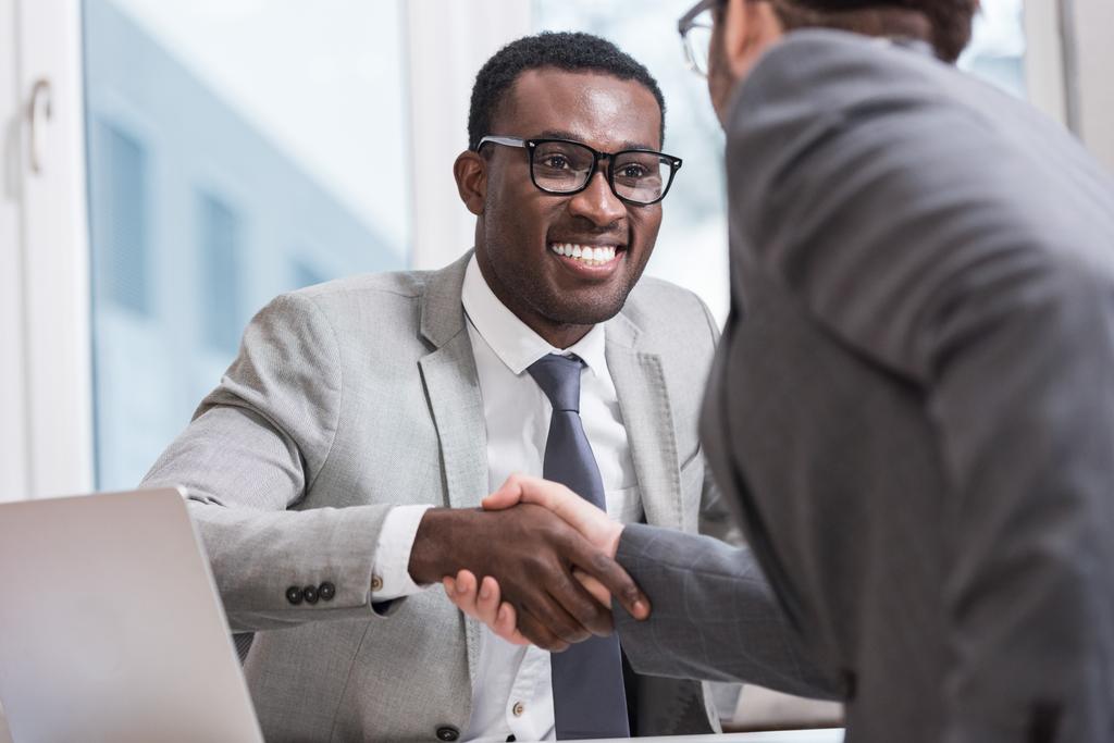 крупним планом вид усміхнених багатоетнічних бізнесменів тремтять руками в офісі
 - Фото, зображення