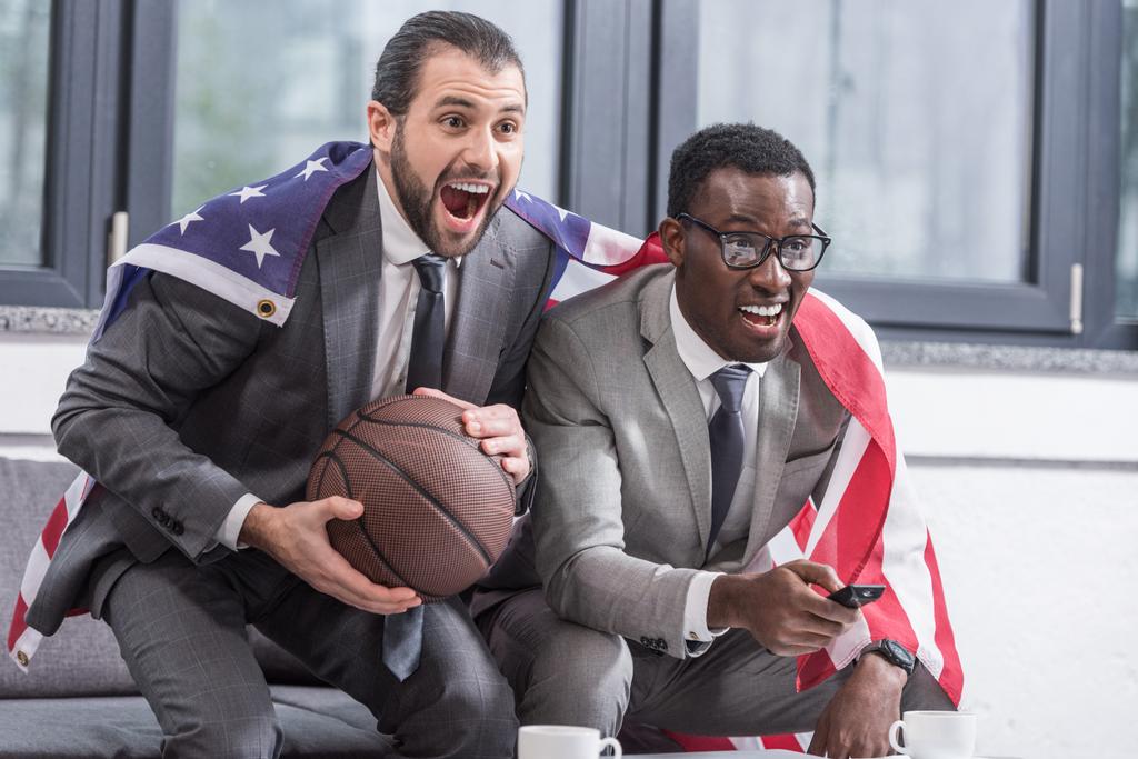 parceiros de negócios multiculturais felizes com bandeira americana assistindo jogo de basquete no escritório
 - Foto, Imagem
