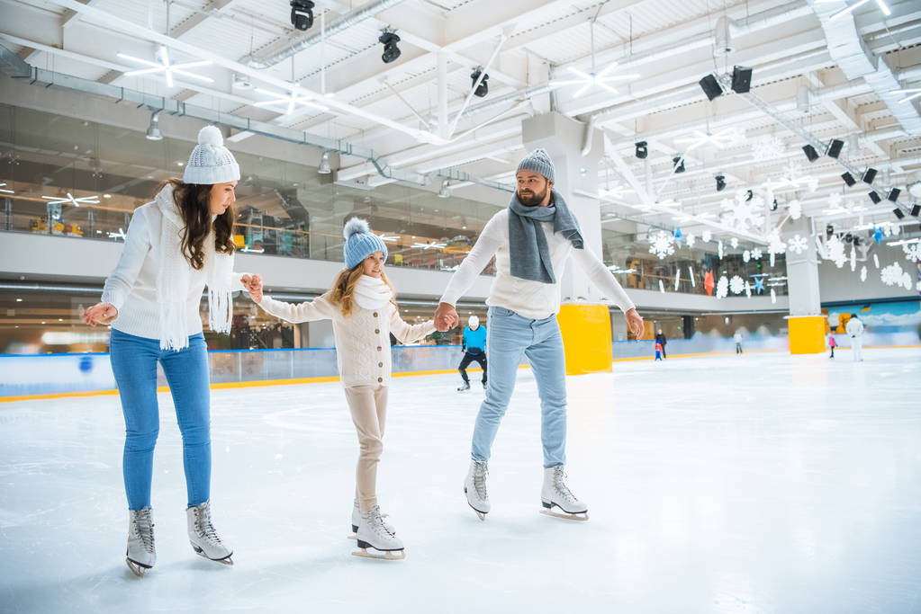 heureux famille tenant la main tout en patinant ensemble sur la patinoire
 - Photo, image