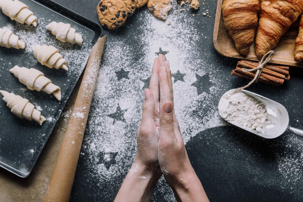imagen recortada de la mujer frotando harina entre las palmas de las manos sobre la mesa con masa para croissants en la bandeja y los ingredientes
  - Foto, imagen