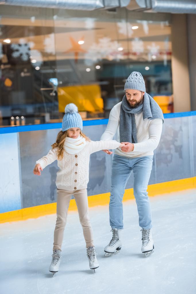 父はアイス スケート リンクでスケートをするには小さな娘を助ける - 写真・画像