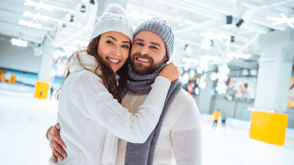 πορτρέτο του ευτυχισμένο ζευγάρι αγκαλιάζει και κοιτάζοντας κάμερα στο παγοδρόμιο - Φωτογραφία, εικόνα