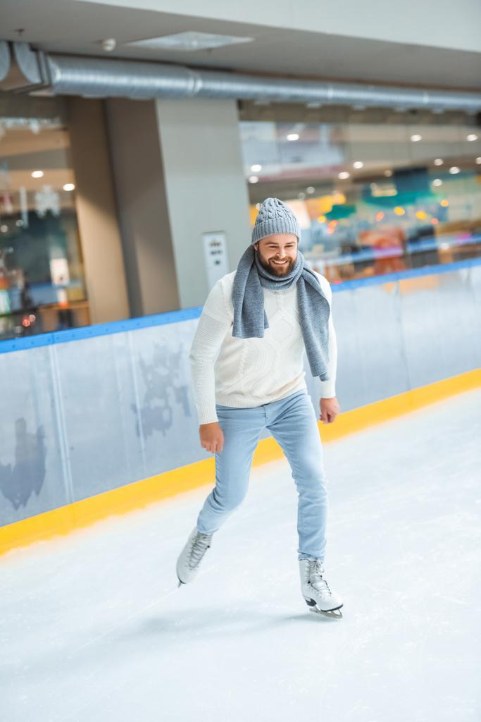 bearded man in knitted hat and sweater skating on ice rink - Photo, Image