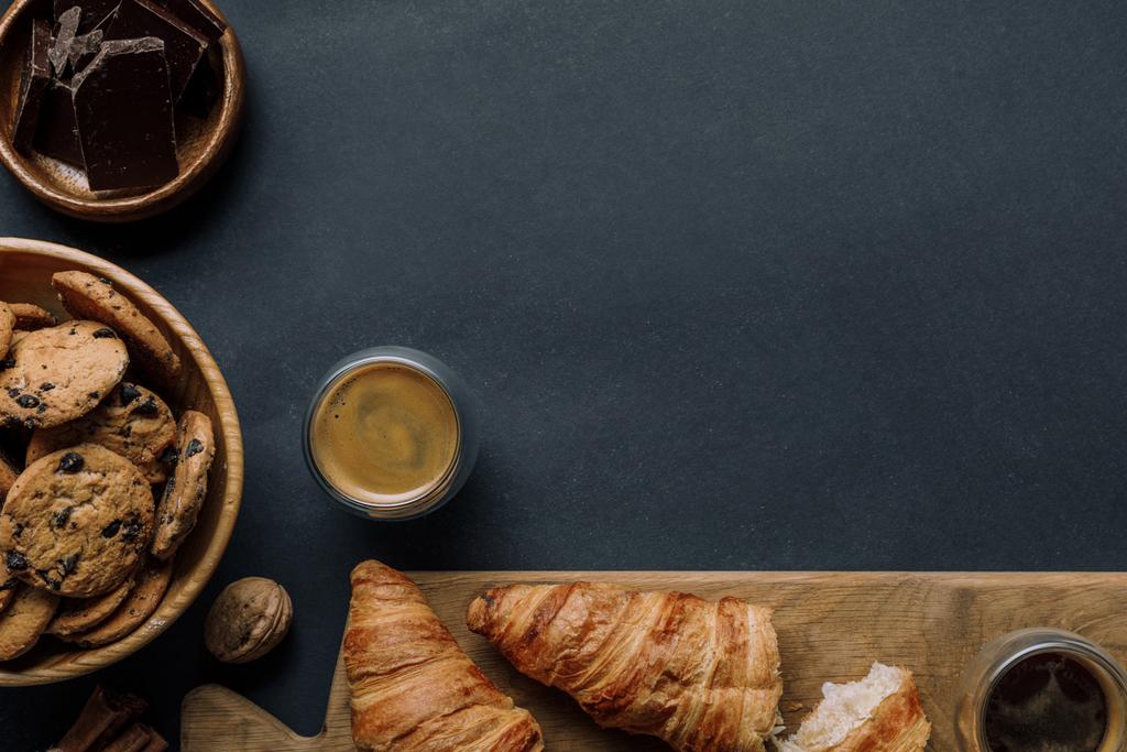 vista dall'alto di cannella, caffè, croissant, cioccolato e biscotti sul tavolo nero
 - Foto, immagini