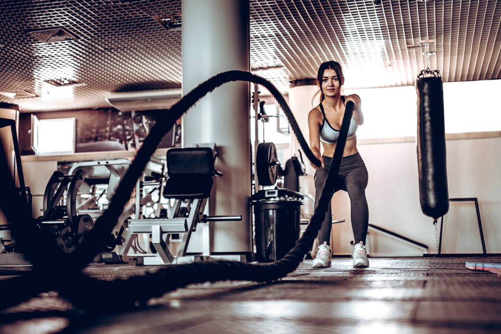 Powerful attractive muscular woman trainer do battle workout with ropes at the gym. Concept:power, strength, healthy lifestyle, sport. - Photo, Image