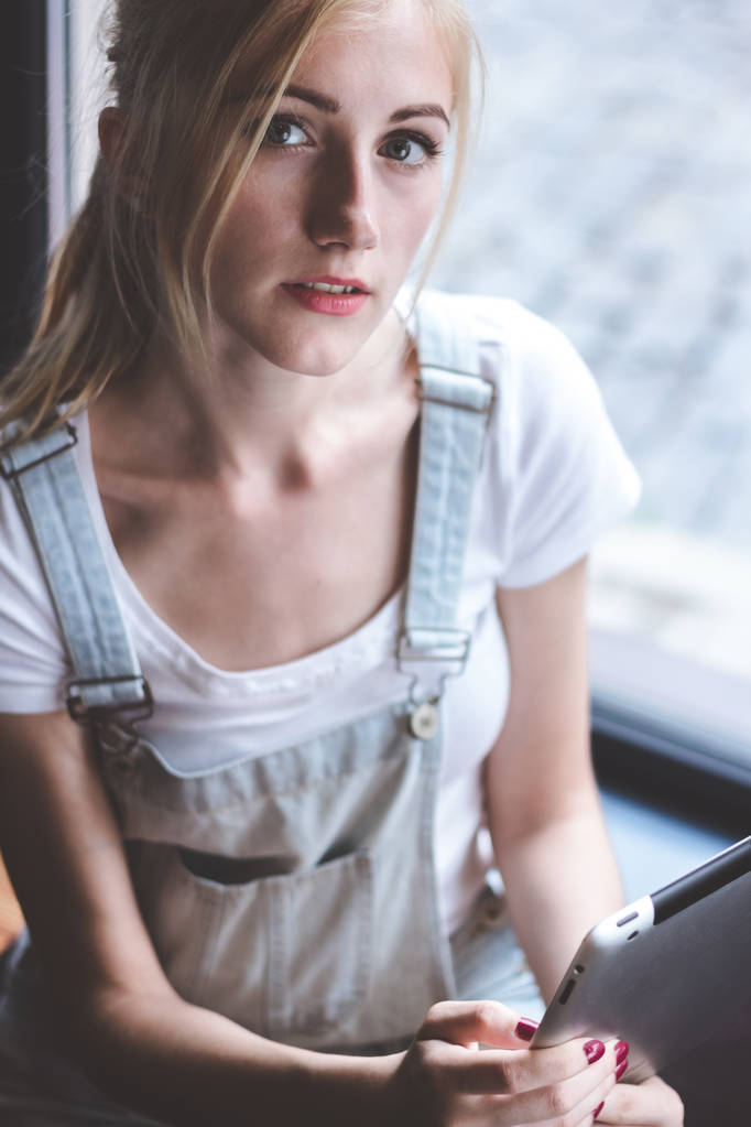 Ter oportunidade de trabalhar em qualquer lugar.Vista superior da jovem mulher alegre segurando tablet digital enquanto está sentado no balcão de madeira no café
. - Foto, Imagem