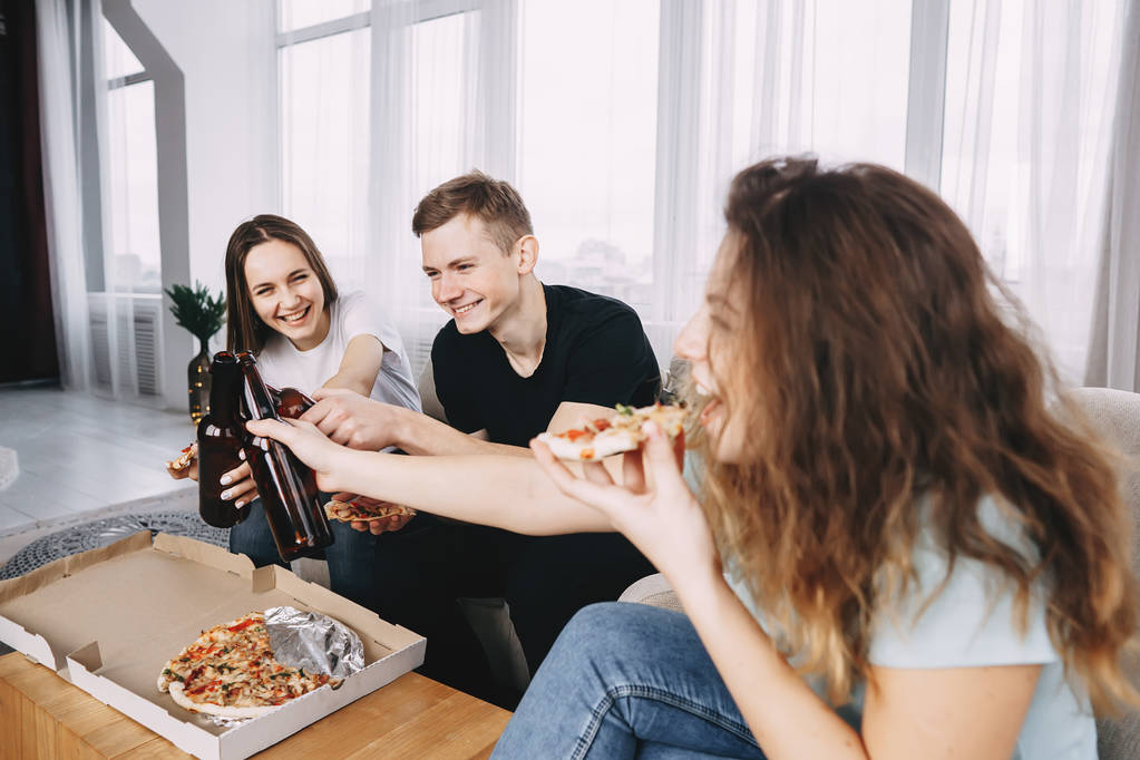 друзья едят пиццу и пьют пиво, звенящие бутылки
 - Фото, изображение